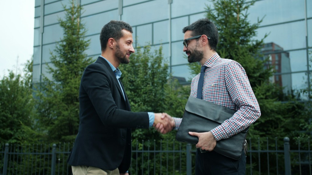 A picture depicting a seller shaking the hand of a buyer in a seller carry transaction