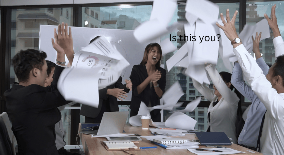 Business team throwing papers in the air in a chaotic office meeting room with the text 'Is this you?' representing the financial chaos new business owners often inherit when they acquire a mom-and-pop operation.