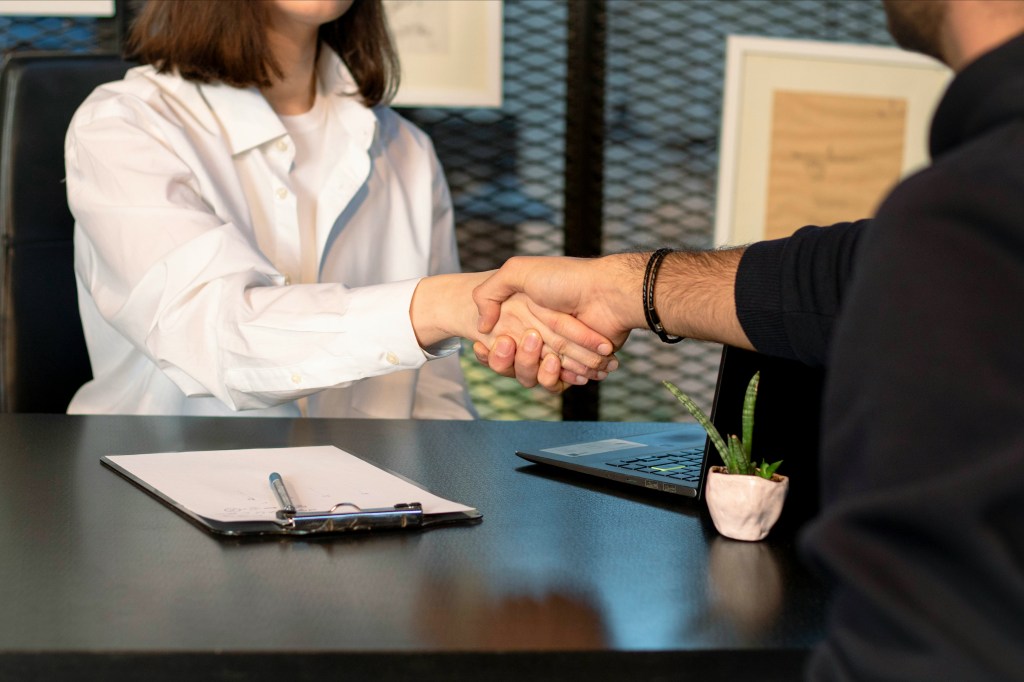 this is a picture of an owner hiring a manager and shaking their hand